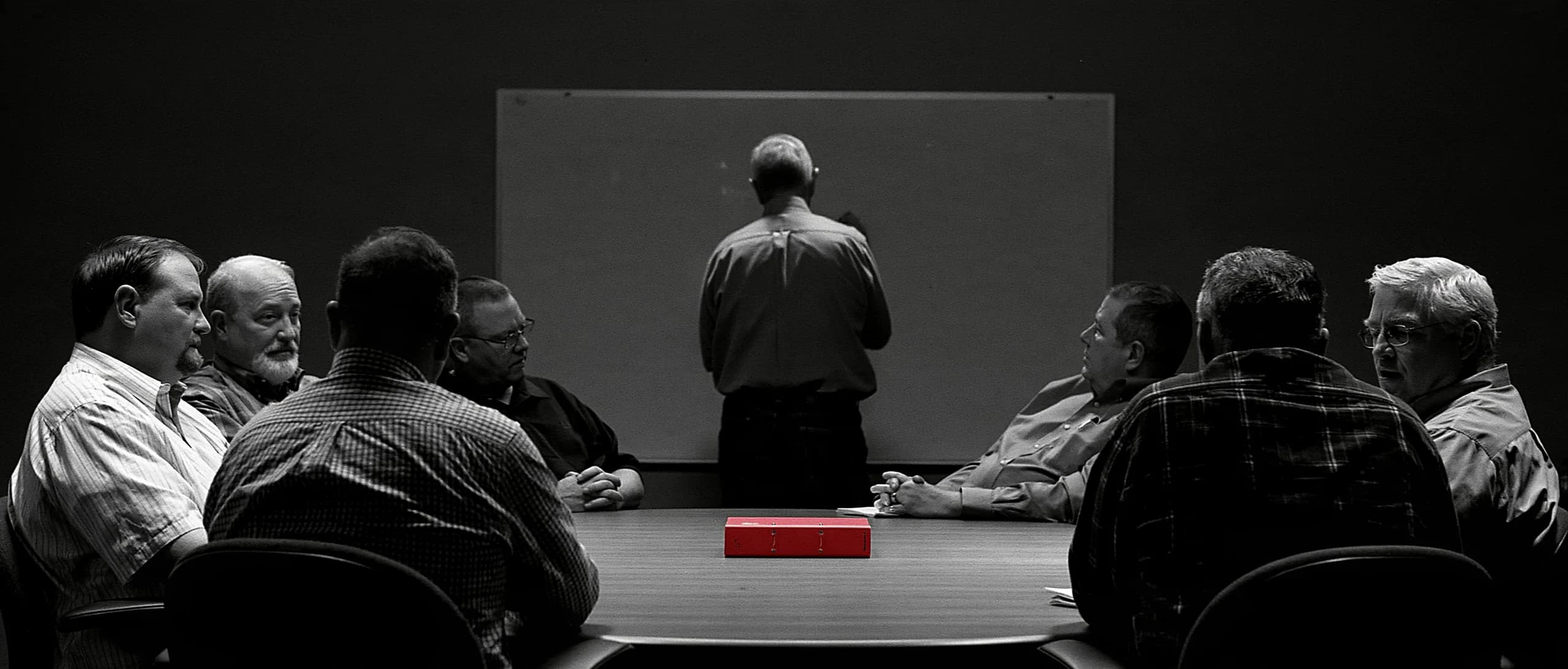 An interim executive leading a weekly management meeting with the client's own managers