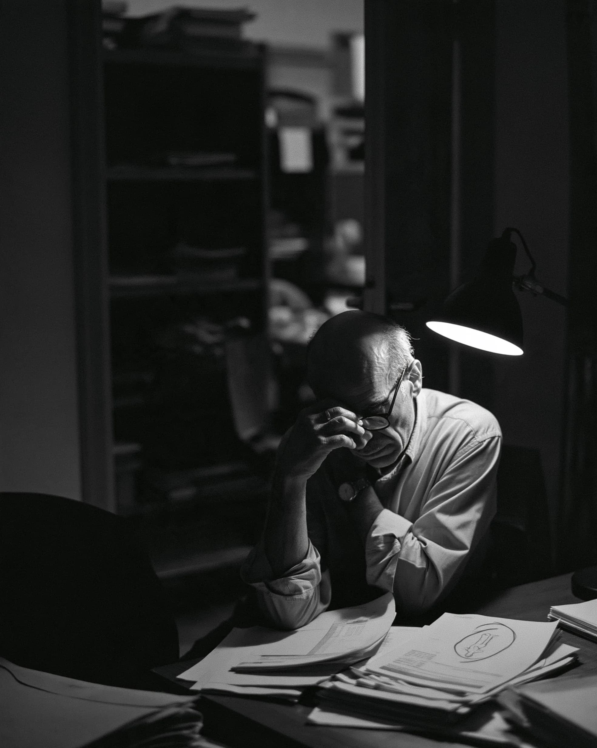 A business owner working late over financial paperwork in a factory office